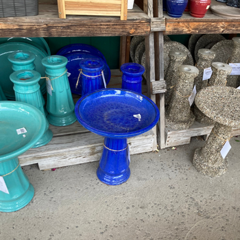 Multiple blue and turquoise bird baths arranged on an outdoor display stand.
